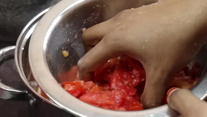 Mash 3 ripe tomatoes by hand.