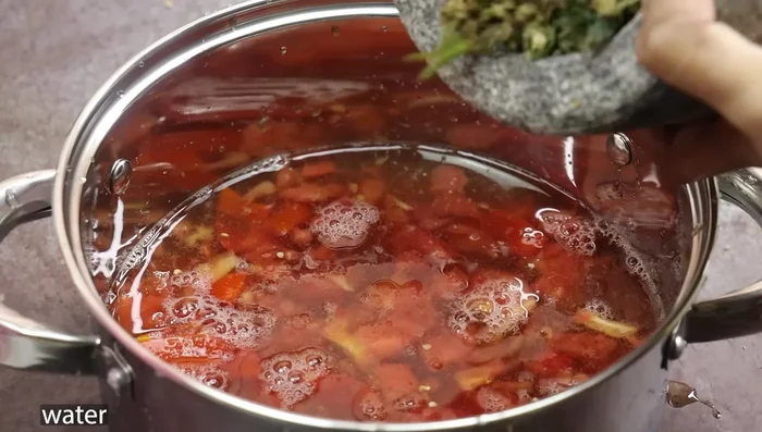 In a bowl, combine tamarind juice, mashed tomatoes, water, the ground spice mixture, turmeric powder, and salt.
