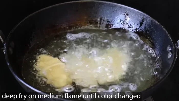 Heat oil in a frying pan over medium heat. Add the flattened dough pieces and fry until lightly browned on both sides, ensuring the raw smell disappears.