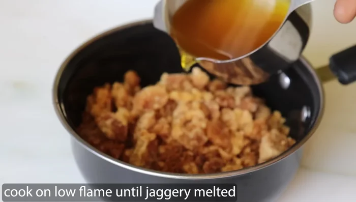 In a saucepan, melt jaggery with ghee over low heat until dissolved. Let it cool.