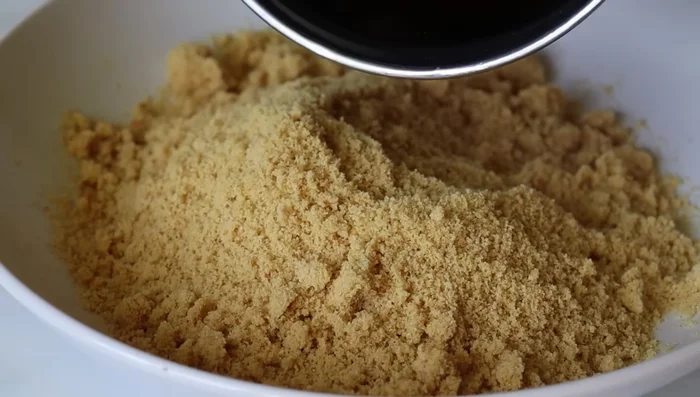 Add the cooled melted jaggery to the powdered fried mixture. Mix well.