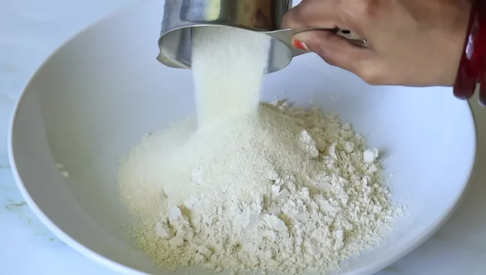 In a mixing bowl, combine wheat flour, semolina, peanut flour, and ghee. Mix well with your hands until the ghee coats the flour and the mixture holds its shape when pressed.