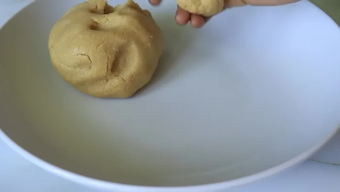 Roll the dough into small balls and flatten them into pancake shapes.